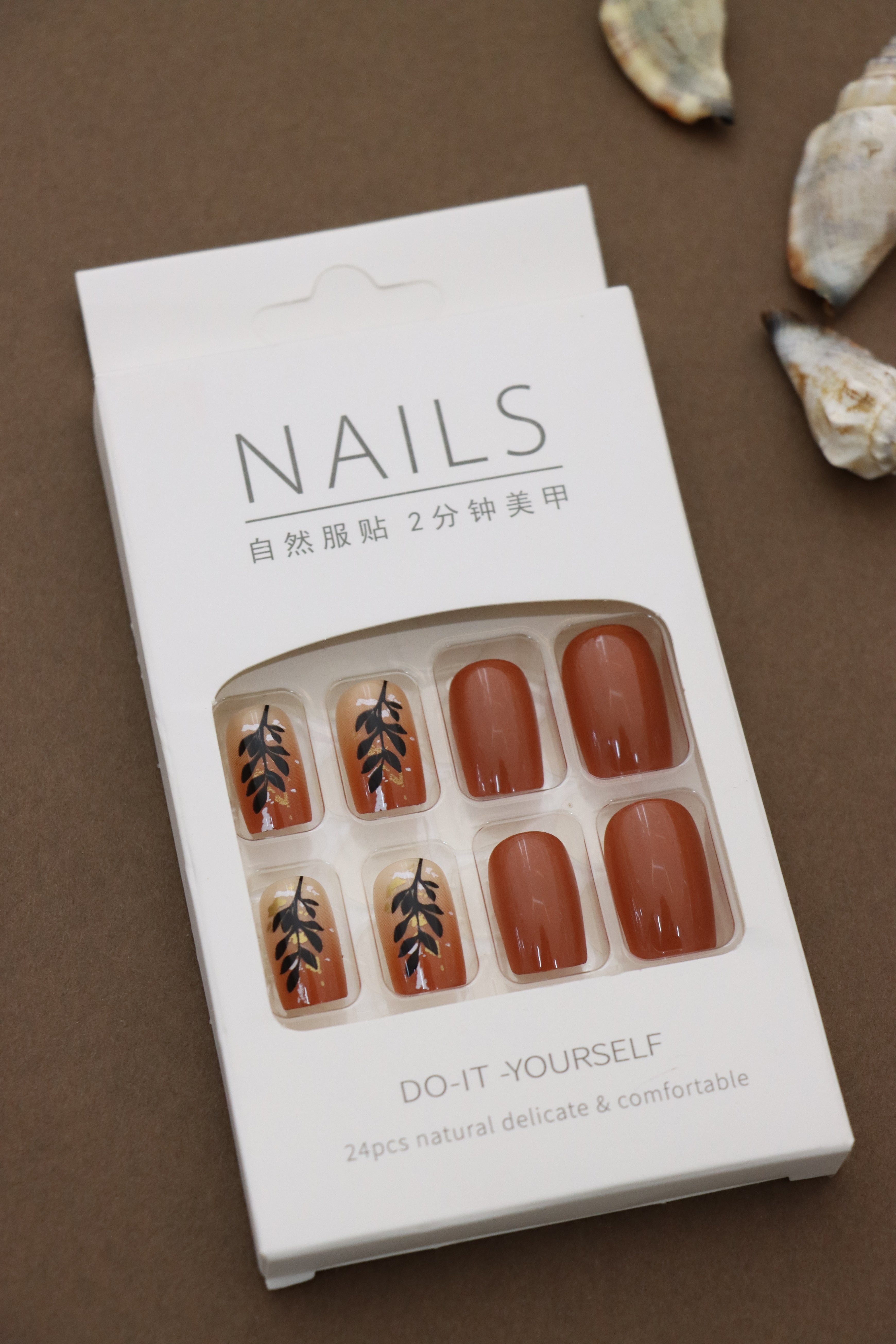 Warm & Earthy: Terracotta Nails with Elegant Black Leaf Art. Embrace Nature's Charm with a Stylish and Sophisticated Look. Perfect for an Autumn-inspired Vibe!