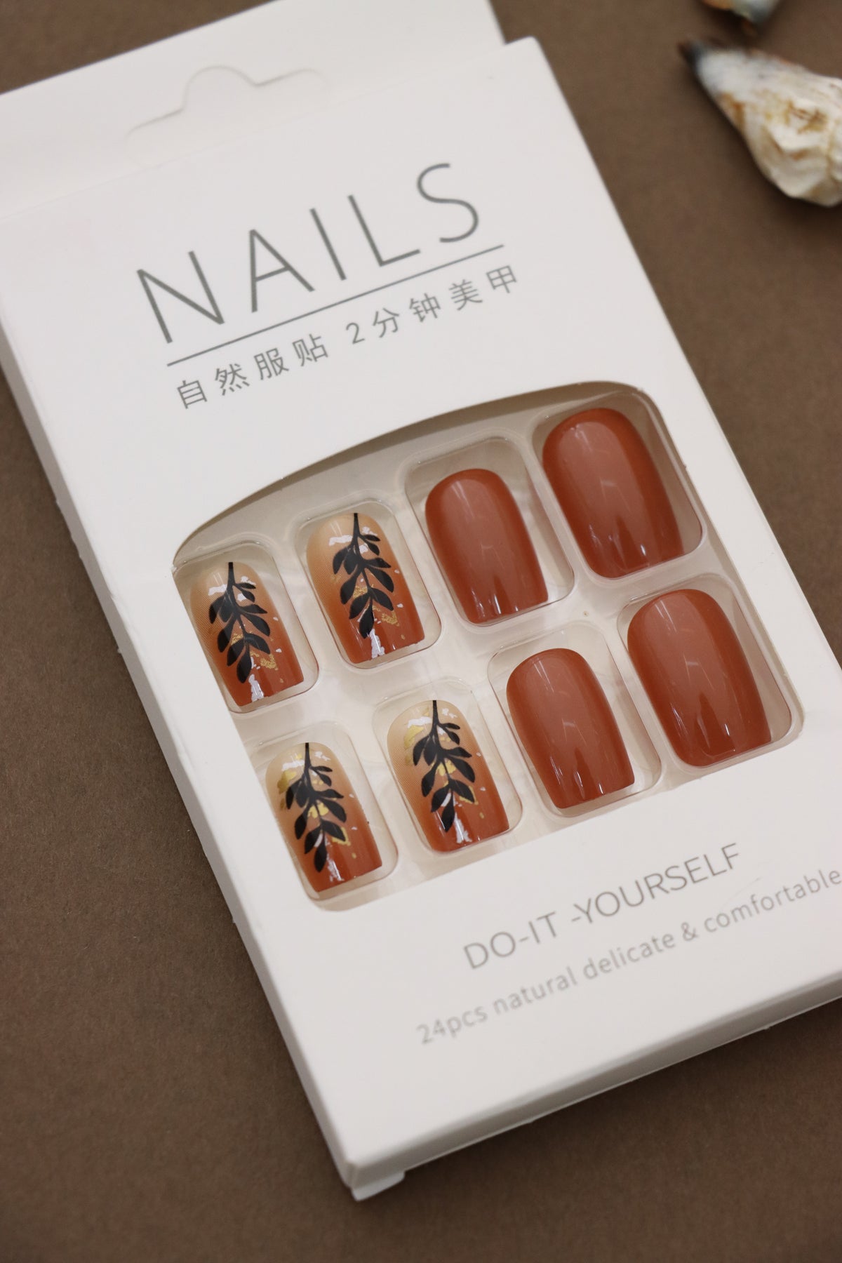 Warm & Earthy: Terracotta Nails with Elegant Black Leaf Art. Embrace Nature's Charm with a Stylish and Sophisticated Look. Perfect for an Autumn-inspired Vibe!